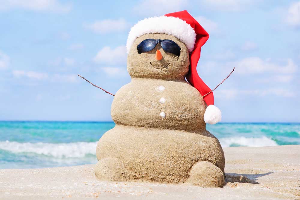 Sand snow man on beach with sun glasses